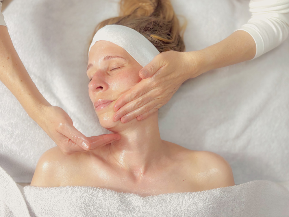 Eine Kunden erhält zusätzlich zu ihrer kosmetischen Behandlung eine Gesichtsmassage