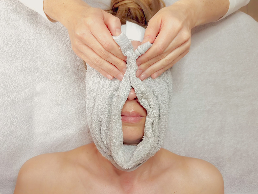eine Kundin erhält während ihrer kosmetischen Behandlung auch ein Wellnessangebot